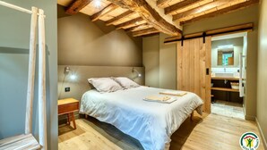 A bedroom with a wooden ceiling, a bed with white bedding, a bedside table, and a nightstand. - Gîtes de France® - The Cottage (BOUDEVILLE)
