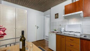 A compact kitchen with wooden cabinets, a built-in oven, and a gas stove. - Cozy apartment in Jadranovo with WiFi (Jadranovo)