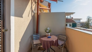 A small balcony with a round table and two chairs, a potted plant, and a view of the neighborhood. - Cozy apartment in Jadranovo with WiFi (Jadranovo)