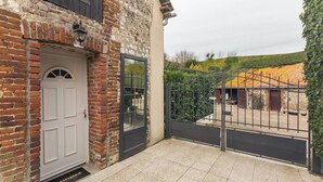 A stone building with a white door and a black gate. - Gîtes de France® - Le Four à Chaux (CRIEL SUR MER)