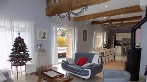 A living room with a Christmas tree, a sofa, a coffee table, and a fireplace. - Gîtes de France® - Le Neuf-Moulin (SAINT CRESPIN)