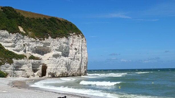 Un paysage côtier avec de hautes falaises blanches, une plage et l’océan.