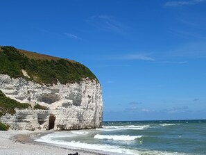 A coastal landscape with white cliffs, a beach, and the ocean.