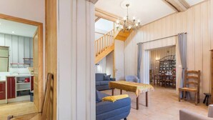 Un amplio salón con un sofá azul, una mesa de centro de madera y una escalera que lleva a un piso superior.