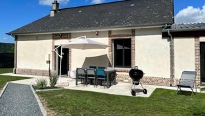 A house with a patio area featuring a table and chairs, a barbecue grill, and a covered seating area.