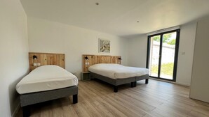 A modern bedroom with two beds, wooden headboards, a large window, and a painting on the wall.