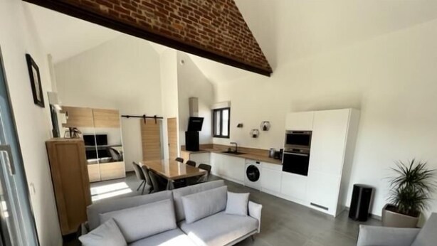 A modern living room with a sofa, coffee table, and a dining area.