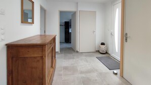 Un couloir avec un banc en bois, un miroir et une porte donnant sur une cuisine.
