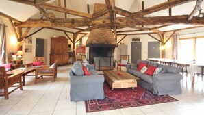 A spacious living room with exposed wooden beams, a fireplace, and a large sofa set.