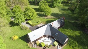A two-story house with a sloped roof, a patio with outdoor furniture, and a well-maintained lawn.