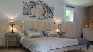 A bedroom with a bed, two bedside tables, a window, and wall art.