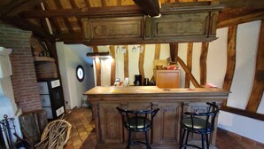 Una cocina rústica con una isla de madera, dos taburetes de bar y una chimenea de ladrillo.