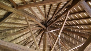 Estructura de techo de madera con una viga central y lámpara colgante.