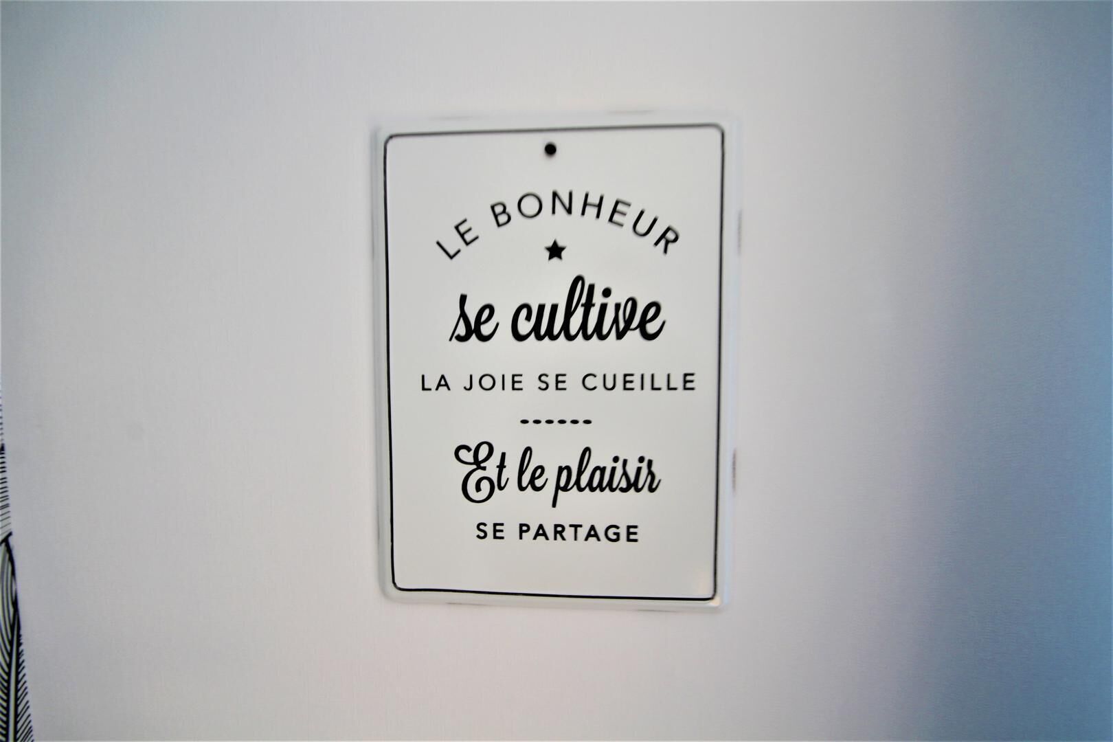 Une enseigne fixée au mur, avec un texte en français.