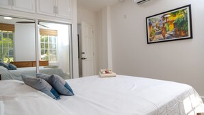 Ein Schlafzimmer mit einem großen Bett, weißer Bettwäsche, einem Bild an der Wand und einer Klimaanlage.