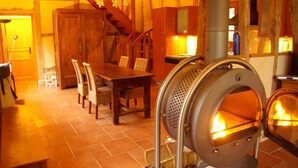 Un interno rustico con un tavolo da pranzo in legno, sedie, una scala e un camino a legna.