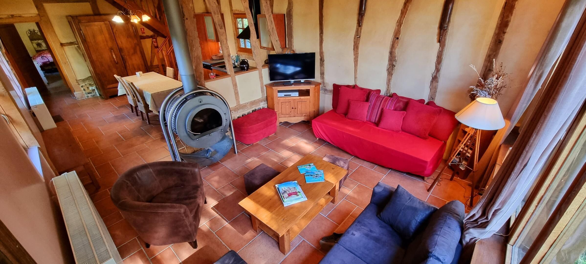A cozy living area with a red sofa, a wooden coffee table, a fireplace, and a television.