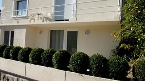 A two-story building with a balcony, a window with a shutter, and a small circular window.