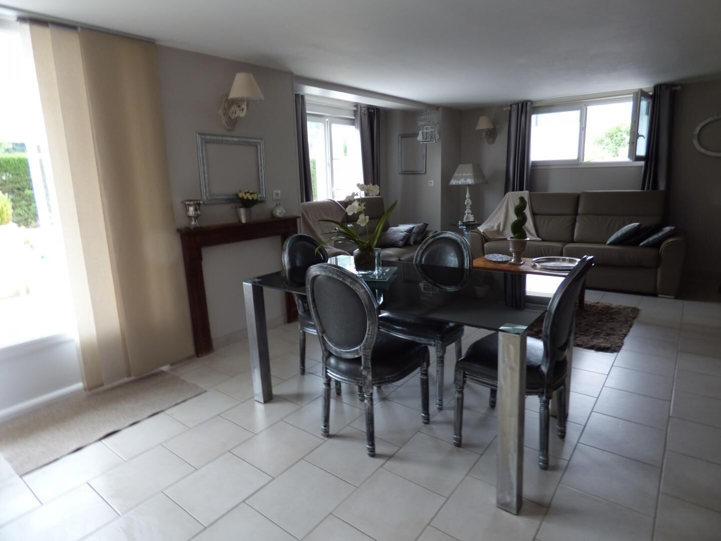 Een moderne eetruimte met een glazen tafel en stoelen, een bank en een open haard.