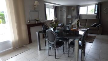 Een moderne eetruimte met een glazen tafel en stoelen, een bank en een open haard.