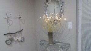 A room with a clear glass console table, a decorative mirror, and a wall-mounted heart-shaped decoration.
