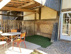 Relax in a charming outdoor space with a pergola, round table, and two chairs.