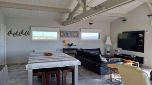 Un salón amplio con una mesa de comedor, sofá de cuero negro y televisor de pantalla plana.