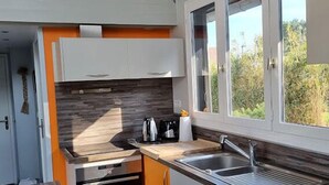 Una cocina moderna con horno empotrado, un lavabo y ventana con vistas a zonas verdes.