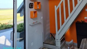 Un interior moderno con una escalera, un vidrio que da al exterior y unidades de almacenaje color naranja.