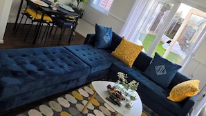 Un soggiorno moderno con un divano angolare blu scuro, un tavolino basso e un tappeto decorato.