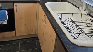 Una cucina con mobili in legno, un piano di lavoro nero, un lavello bianco e una finestra con persiane.