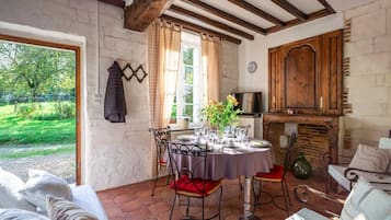 Un comedor con una mesa redonda dispuesta para cuatro personas, una chimenea y vistas al jardín.