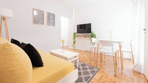 A modern living room with a sofa, a coffee table, a TV, and a dining area with chairs and a table. - MOT Borges 2200 (Buenos Aires)