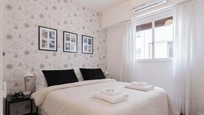 A neatly made bed with white bedding, a nightstand with a lamp, and framed pictures on the wall. - MOT Borges 2200 (Buenos Aires)