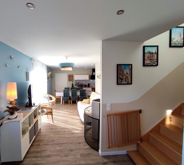 A modern living space with a dining area, kitchen, and staircase. - Gîtes de France® - L' Hirondelle (TURRETOT)