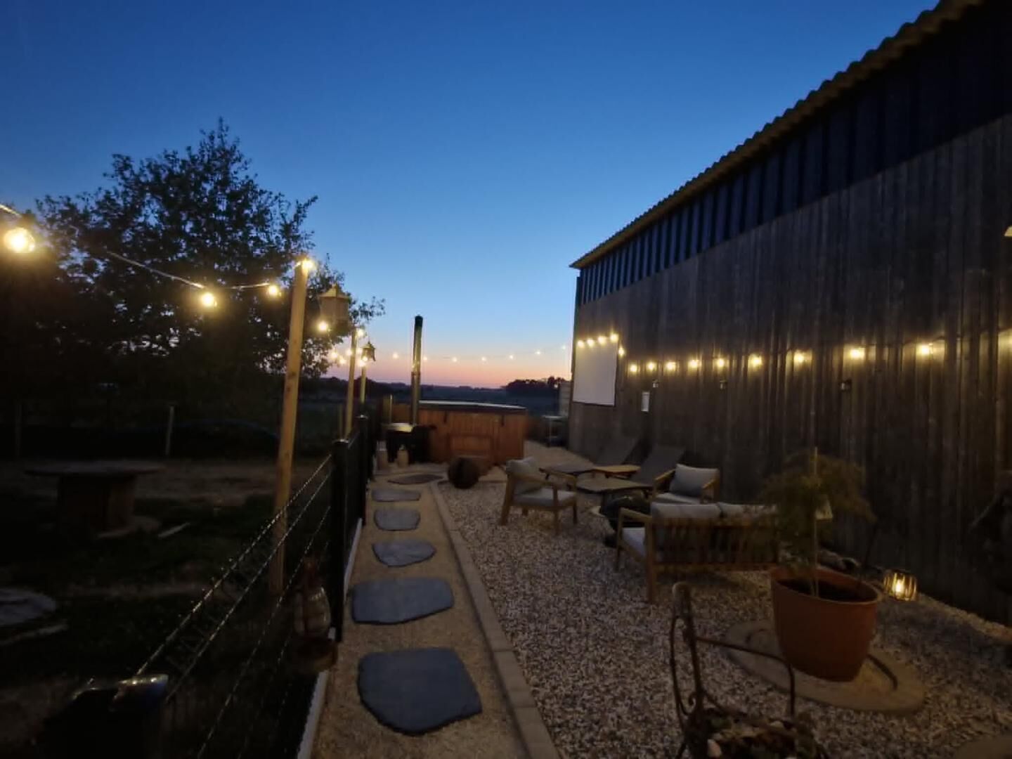 An outdoor patio area with string lights, seating, and a view of the horizon.