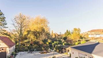 A residential property with a gravel driveway, a garage, and a well-maintained garden with various plants and trees.