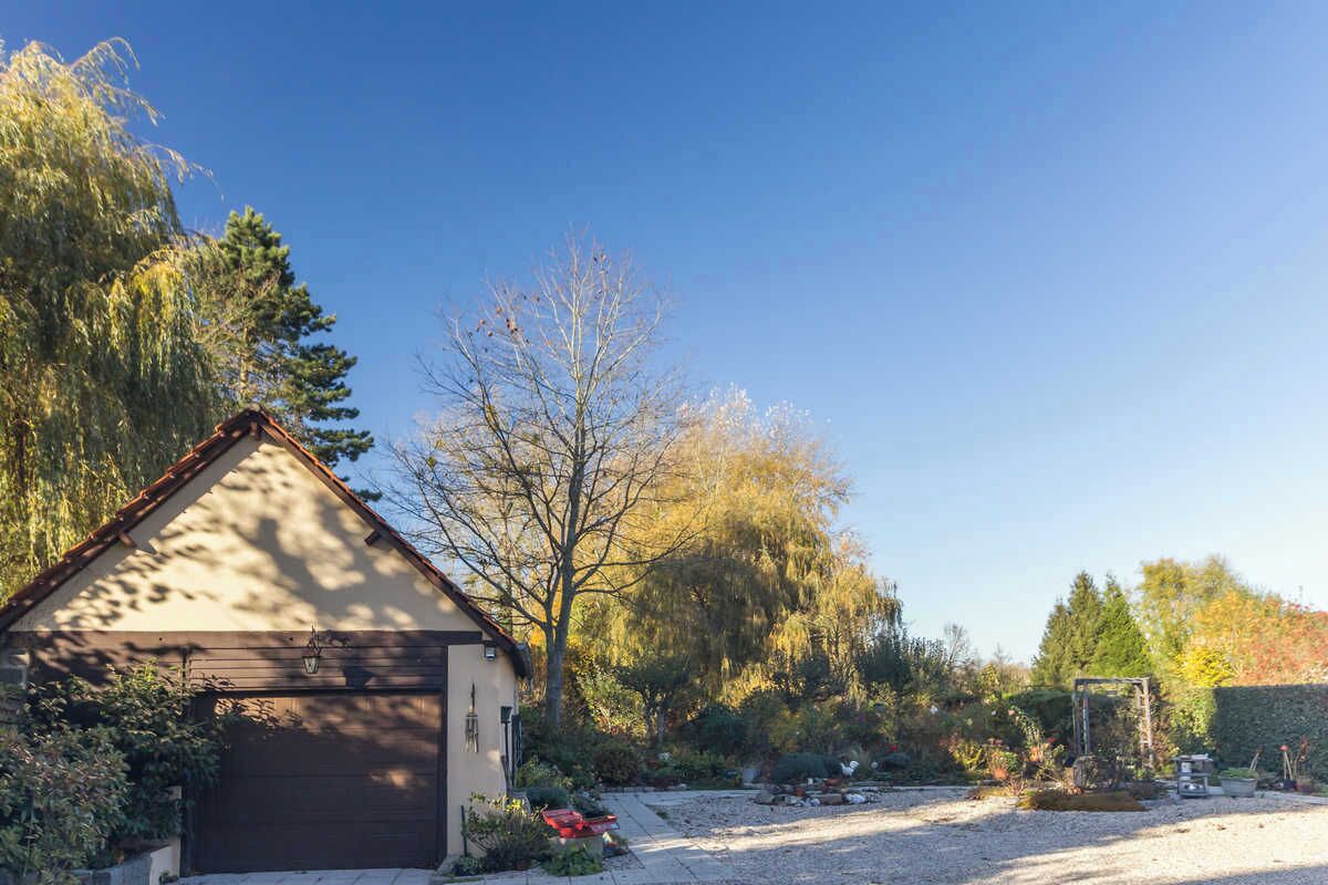 A single-story building with a sloped roof, a garage, and a gravel driveway.