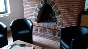 A room with a brick fireplace, two black chairs, and a table with a tray.