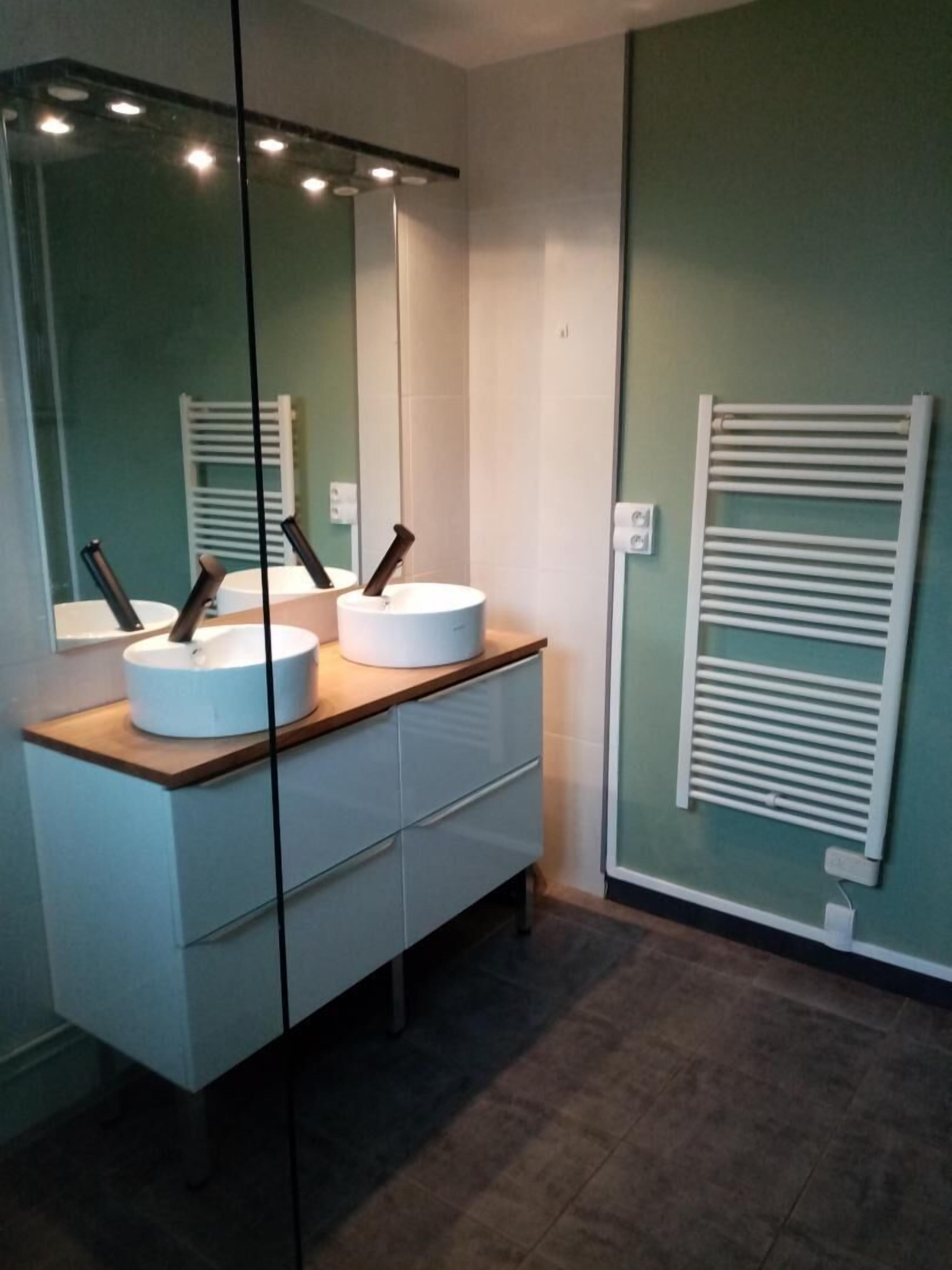 Une salle de bain moderne avec deux lavabos, un miroir et un porte-serviettes.