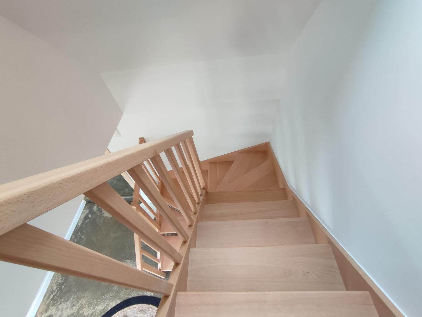 A wooden staircase with a handrail, leading upwards.