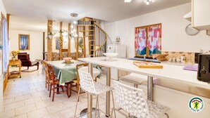 A spacious dining area with a wooden staircase, a kitchen with modern appliances, and a dining table set with chairs.