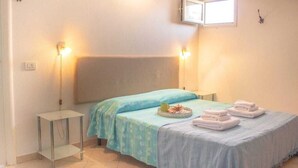 A bedroom with a bed, bedside tables, and a window. - The Grottino (Stintino)