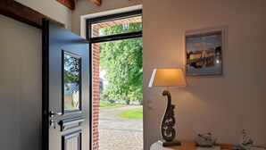 Une porte-fenêtre donnant sur un jardin, avec une lampe et des objets décoratifs placés sur une table en bois.