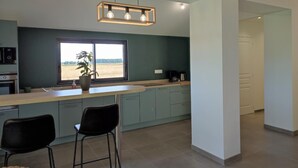 Une cuisine moderne dotée d’une grande fenêtre, de meubles de couleur bleu clair et d’un luminaire suspendu.