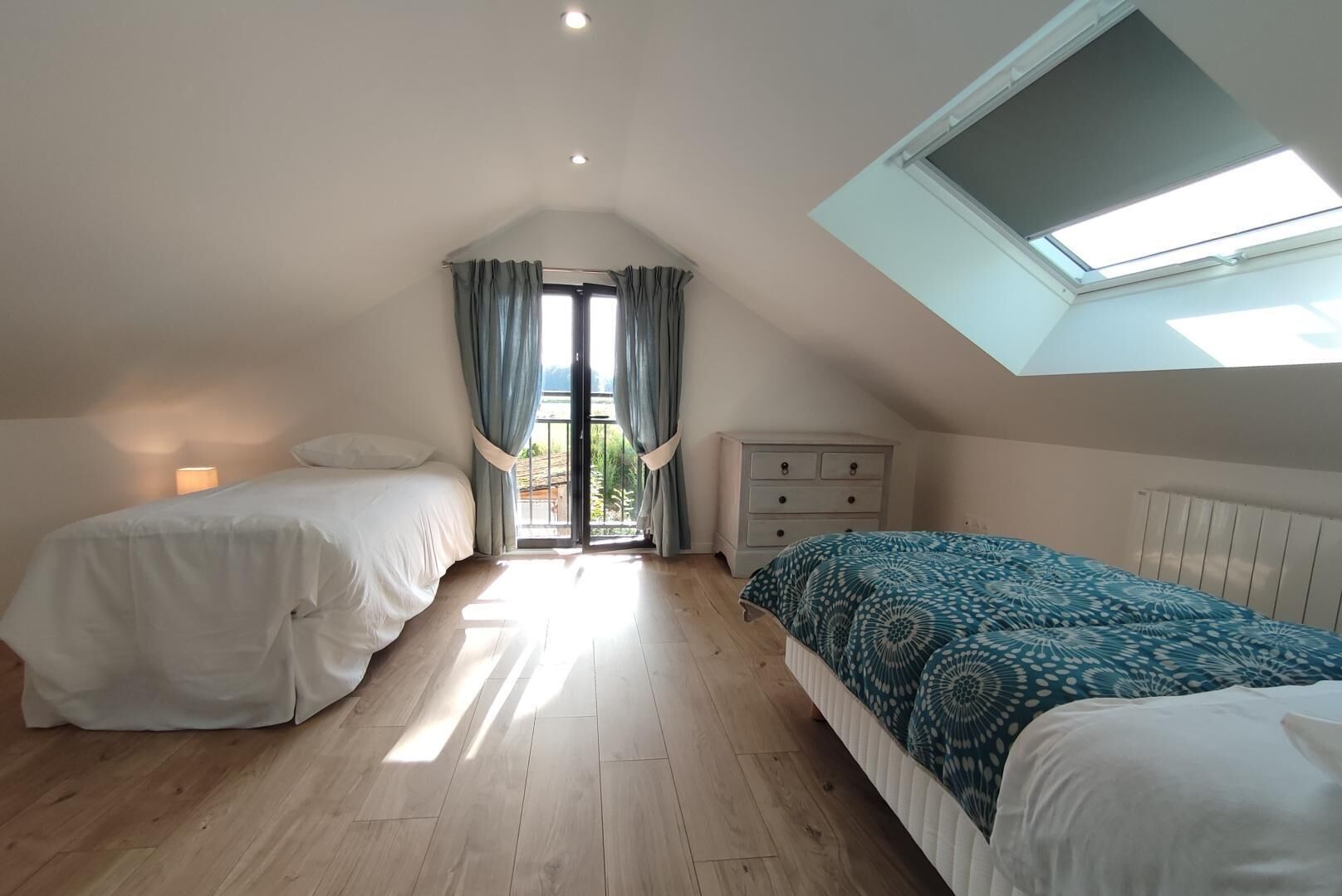 Un dormitorio con dos camas, un tragaluz y vistas al exterior.