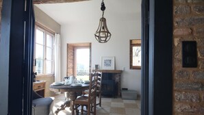 A dining area with a round table, chairs, a hanging light fixture, and a fireplace. - Gîtes de France® - The Orangery (HUGLEVILLE EN CAUX)