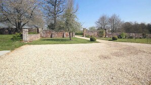 A gravel driveway leading to a brick wall with a small garden area. - Gîtes de France® - The Orangery (HUGLEVILLE EN CAUX)