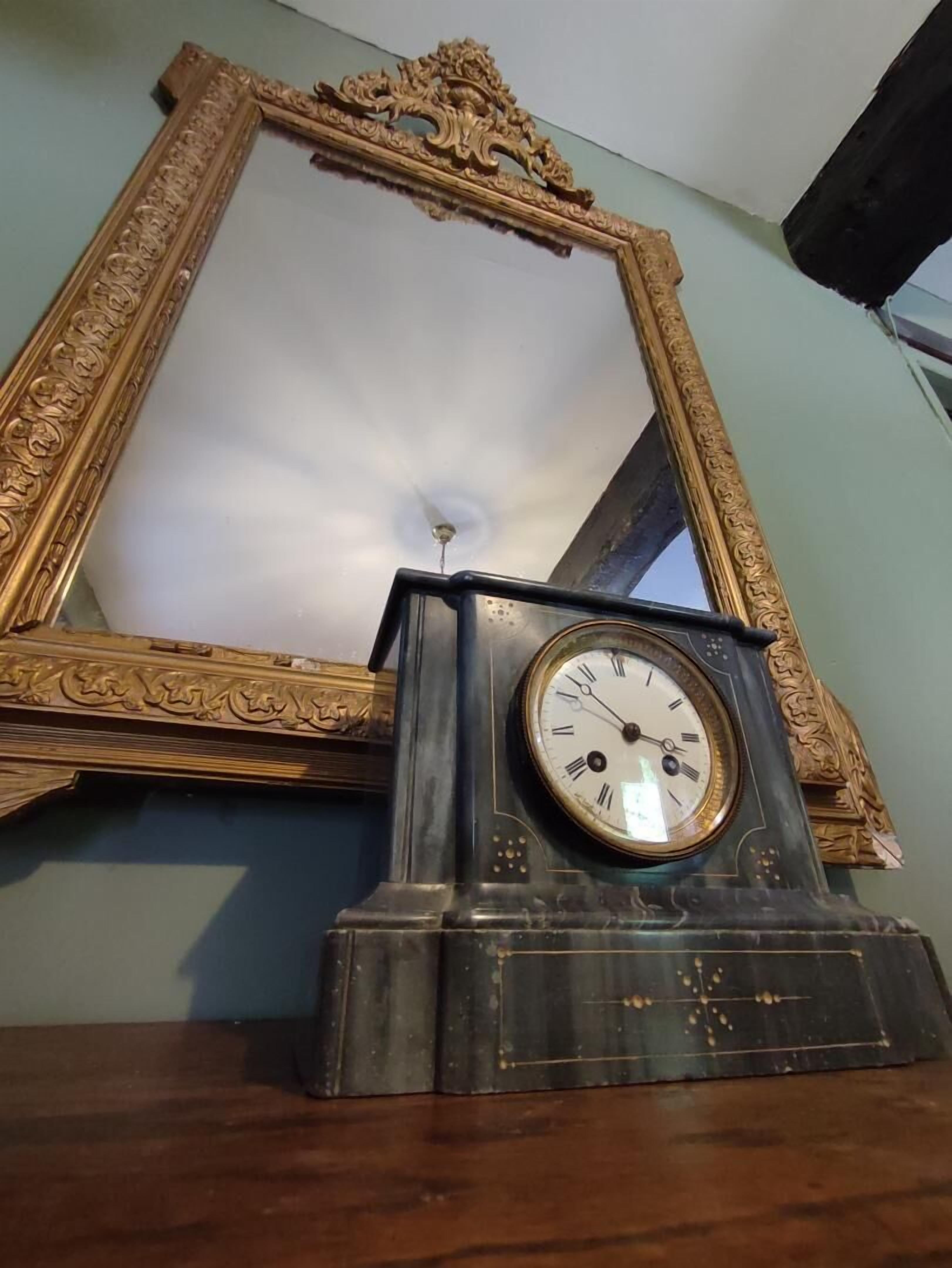 A large ornate mirror with a gold frame and a clock below it.