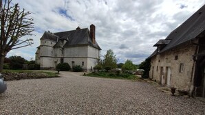 Ein Innenhof mit einem Kiesweg, der zu einem Steinhaus mit einem großen Turm führt.
